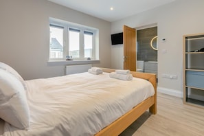 A bedroom with a bed, a window, a TV, a mirror, and a wardrobe. - 4 Bed in Padstow (oc-r32776) (Padstow)
