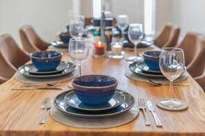 A dining table set with blue bowls, wine glasses, and cutlery, with chairs around it. - 4 Bed in Padstow (oc-r32776) (Padstow)