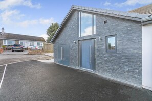 Een modern gebouw met een stenen gevel, grote ramen en een garagepoort.