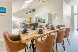 Un espace repas moderne avec une table en bois dressée pour six personnes, entourée de chaises en cuir.