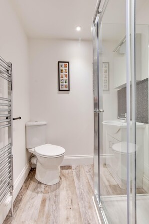 A modern bathroom with a toilet, shower, and glass-enclosed shower area. - 3 Bed in Staithes (oc-wa314) (Staithes)