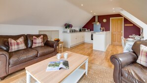 A cozy living room with a brown leather sofa, a wooden coffee table, and a dining area with a white table and chairs. - 1 Bed in Swannington (oc-2206) (Attlebridge)