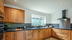 A modern kitchen with wooden cabinets, a black countertop, and a stainless steel range hood. - 2 Bed in Pickering (oc-d32743) (Pickering)
