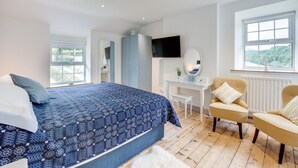 Une chambre à coucher avec un lit, un bureau, une chaise, une télévision et une fenêtre.