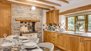 Une cuisine aux murs en pierre, aux meubles en bois et dotée d’un coin repas aménagé pour prendre un repas.