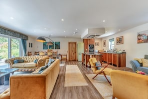 A spacious living area with a sofa set, a dining table, and a kitchen area with wooden cabinets and a countertop. - 3 Bed in Birnam (oc-o32901) (Birnam)
