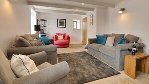 Una sala de estar moderna con dos sofás, un sillón rojo y una pequeña mesa de madera con vasos y una botella.