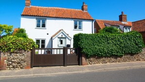 A white house with a red-tiled roof, a stone wall, and a wooden gate. - 3 Bed in Brancaster (oc-2153) (Brancaster)