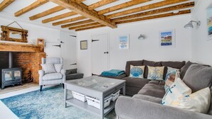 A cozy living room with exposed wooden beams, a fireplace, a sofa, a coffee table, and a rug. - 2 Bed in Southwold (oc-19cs) (Southwold)