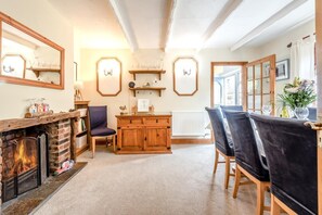 A cozy living room with a fireplace, wooden furniture, and a view of the outside. - 4 Bed in Tenby (oc-pw500a) (Tenby)
