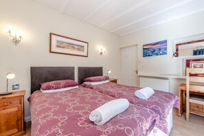 A double bed with a patterned bedspread, bedside lamps, a framed picture on the wall, and a wooden nightstand. - 4 Bed in Tenby (oc-pw500a) (Tenby)
