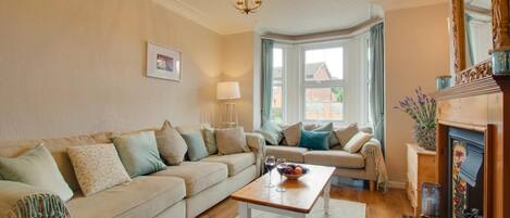 A living room with a beige sofa, a coffee table, and a fireplace.