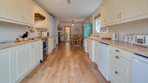 A kitchen with white cabinets, a wooden floor, and a teal refrigerator. - 3 Bed in Heacham (oc-2203) (Heacham)