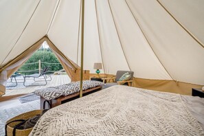A tent with a bed, a table, and a chair.