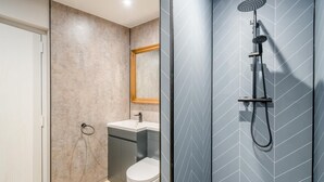 A modern bathroom with a shower, toilet, and sink.