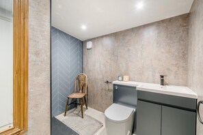 Une salle de bain équipée d’une douche, de toilettes, d’un lavabo et d’une chaise.