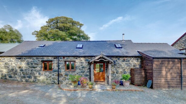 A stone cottage with a wooden door, two windows, and a gravel driveway. - 2 Bed in Tywyn (oc-wah595) (Llanegryn)