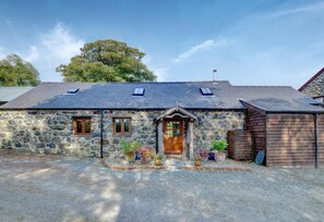 A stone cottage with a wooden door, two windows, and a gravel driveway. - 2 Bed in Tywyn (oc-wah595) (Llanegryn)