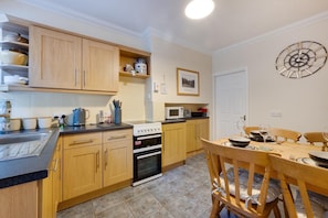 A kitchen with wooden cabinets, a stove, and a dining table set for two.