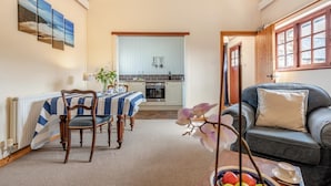 Un soggiorno accogliente con zona pranzo, una cucina sullo sfondo e vista sull'esterno.