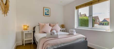 Une chambre à coucher comprenant un lit, des tables de chevet, une fenêtre avec vue et une œuvre d’art accrochée au mur.