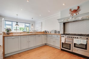 A kitchen with a large island, stainless steel appliances, and a decorative crab on the wall. - 5 Bed in Bodham (oc-2204) (Bodham)