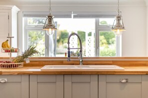 A kitchen with a wooden countertop, a white sink, and a window with a view of greenery. - 5 Bed in Bodham (oc-2204) (Bodham)