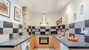 A modern kitchen with a stone accent wall, checkered backsplash, and a central island. - 1 Bed in Richmond (oc-k32861) (Richmond)