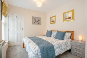 A bedroom with a bed, bedside tables, a radiator, and framed pictures on the wall.