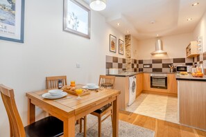 A compact kitchen with a central island, a dining area with a wooden table, and a small seating arrangement.
