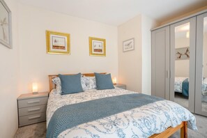 A bedroom with a bed, bedside tables, a wardrobe, and framed pictures on the wall.