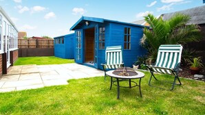 A blue house with a patio, two chairs, and a small table. - 2 Bed in Walcott (oc-2209) (Walcott)