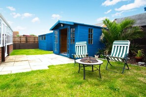 A blue house with a patio, two chairs, and a small table. - 2 Bed in Walcott (oc-2209) (Walcott)
