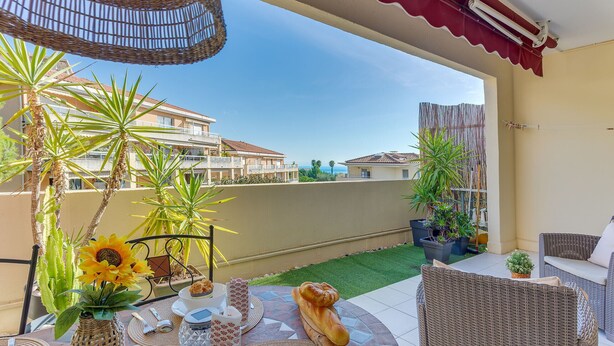 A patio with a wicker table, a wicker chair, a sun-shaped vase, and a loaf of bread. - IMPERIA AP4490 by RIVIERA HOLIDAY HOMES (Niza)