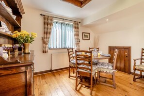 A dining area with wooden chairs and a round table, a radiator, and a window with curtains. - 2 Bed in Caersws (oc-waa322) (Trefeglwys)