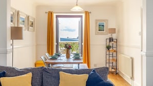 A dining area with a table set for four, a view of the outdoors, and a radiator on the wall. - 2 Bed in Newquay (oc-j32859) (Newquay)