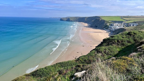 A coastal landscape with a beach, cliffs, and buildings. - 2 Bed in Newquay (oc-j32859) (Newquay)