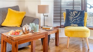 A living room with a wooden coffee table, a yellow armchair, a grey sofa, and a lamp. - 2 Bed in Newquay (oc-j32859) (Newquay)