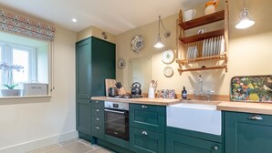 A kitchen with teal cabinetry, a built-in oven, a sink, and a window with a plant. - 2 Bed in Brassington (oc-dcgol) (Brassington)