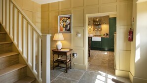 A staircase leading to a kitchen area with a green door, a framed floral painting, and a table with a lamp. - 2 Bed in Brassington (oc-dcgol) (Brassington)