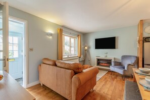 Ein Wohnzimmer mit Sofa, Fernseher, Kamin und Essbereich.
