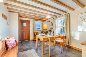 A cozy dining area with wooden furniture, a table set for two, and a window with curtains. - 2 Bed in Penrhyndeudraeth (oc-wag442) (Penrhyndeudraeth)
