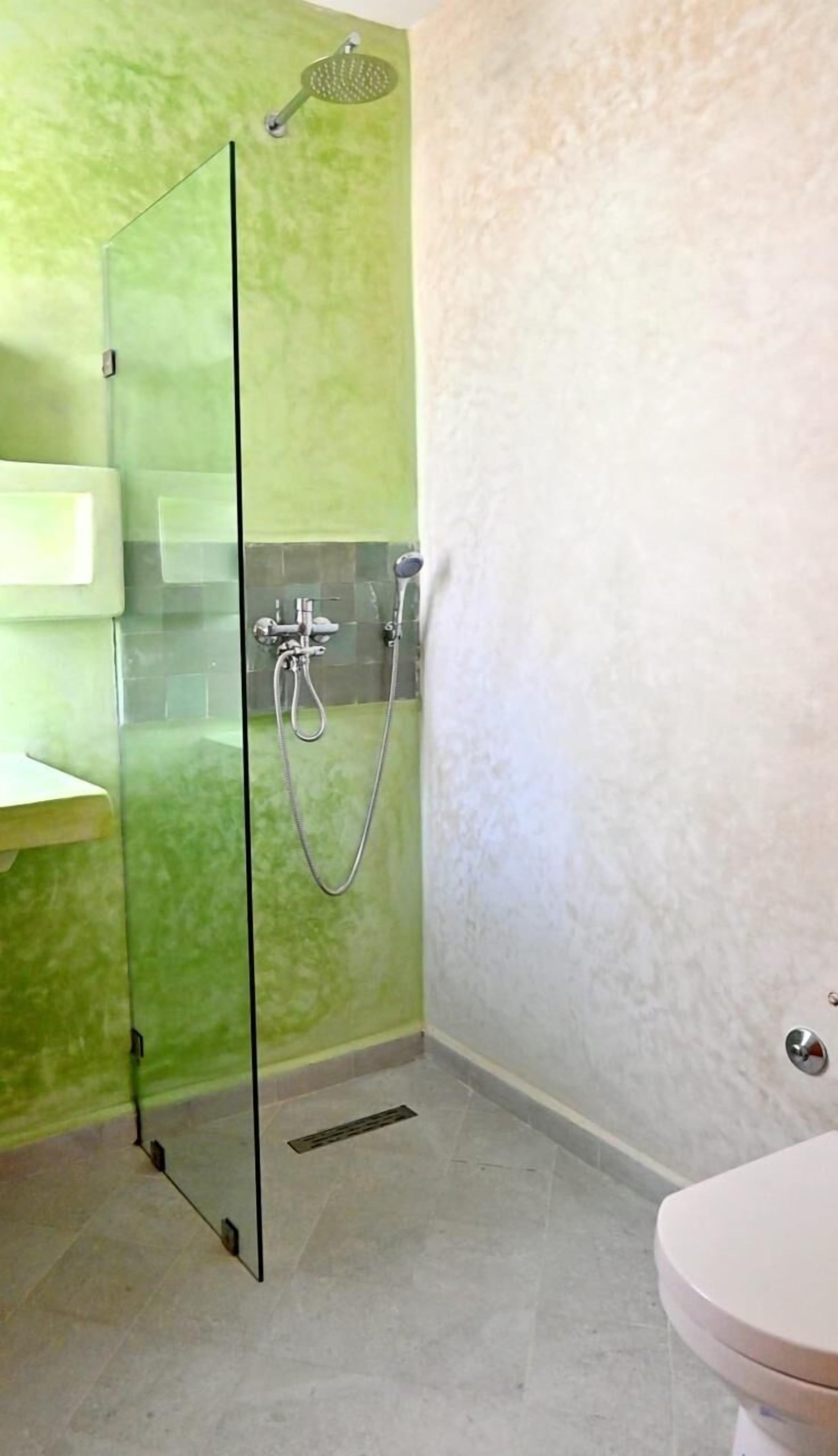 A bathroom with a glass shower enclosure, a toilet, and a sink.