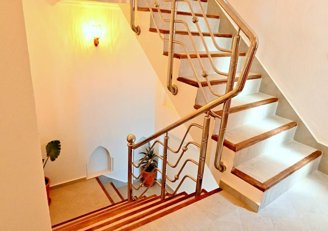 Una escalera con barandilla de metal y escalones de madera.