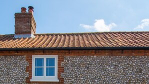 A stone building with a tiled roof, two windows, and a green door. - 1 Bed in Holt (oc-2184) (Holt)