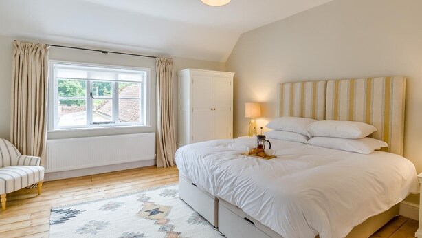 A bedroom with a large bed, a window with curtains, a radiator, a wardrobe, and a bedside table with a lamp. - 2 Bed in Mannington (oc-g32751) (Mannington)