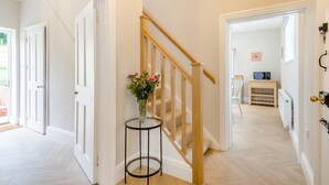 A hallway with a wooden staircase, white doors, and a small table with a vase of flowers. - 2 Bed in Mannington (oc-g32751) (Mannington)