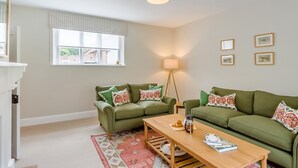 A living room with two green sofas, a wooden coffee table, a floor lamp, and a window with blinds. - 2 Bed in Mannington (oc-g32751) (Mannington)