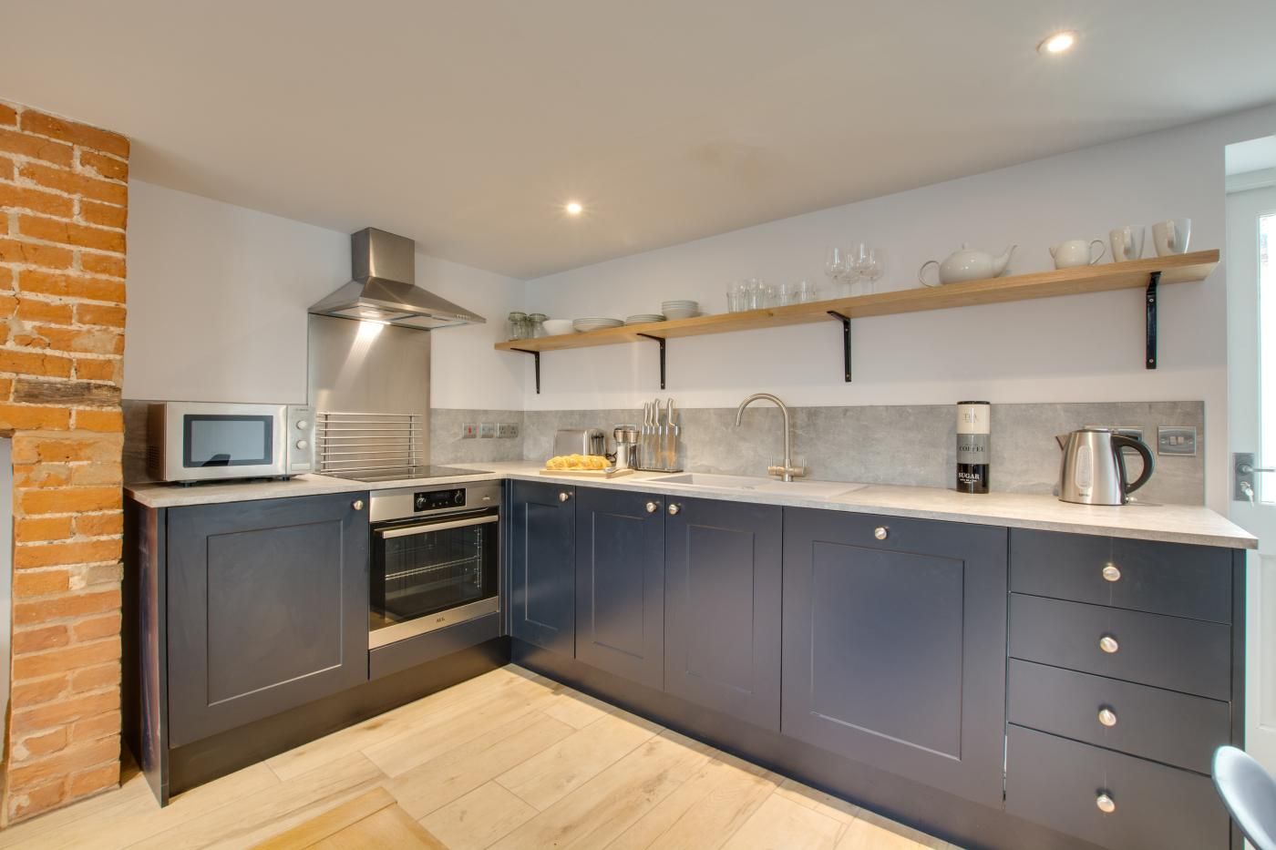 A modern kitchen with dark cabinets, a microwave, an oven, a sink, and a coffee machine.