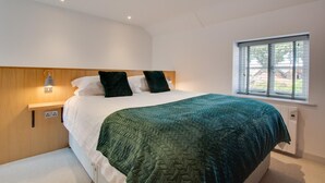 Une chambre à coucher moderne avec un lit, une table de chevet, une fenêtre et un luminaire fixé au mur.